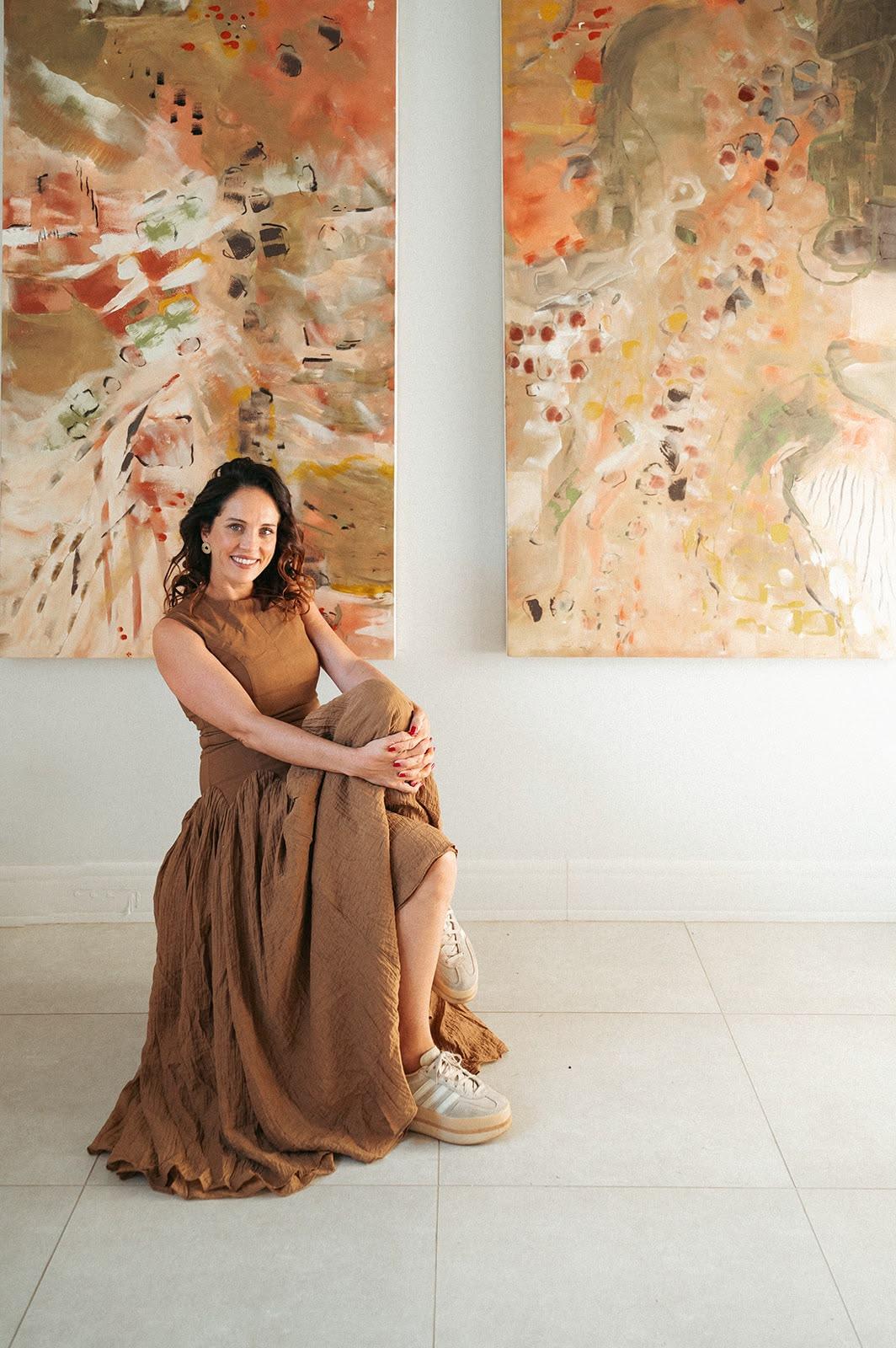 Hayley Lombard seated beneath two large commissioned works in a curated interior